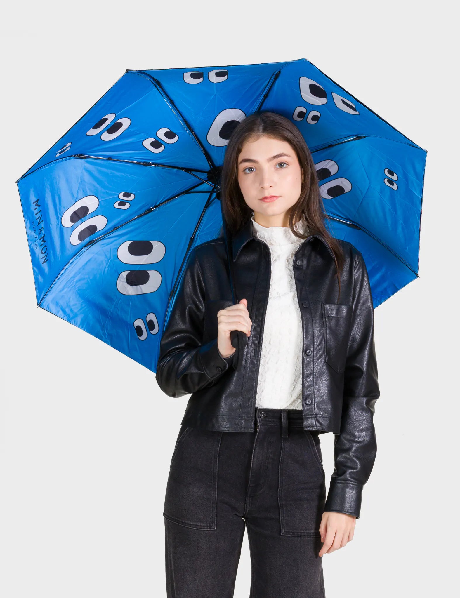 Person holding a blue umbrella with white patterns on a plain background
