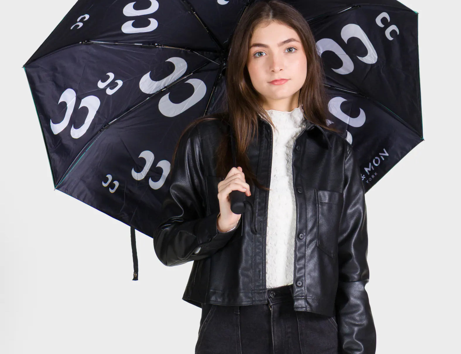 Person holding a black umbrella with white patterns against a white background