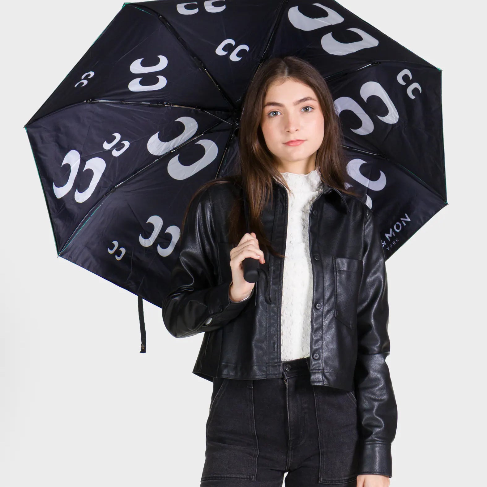 Person holding a black umbrella with white patterns against a white background