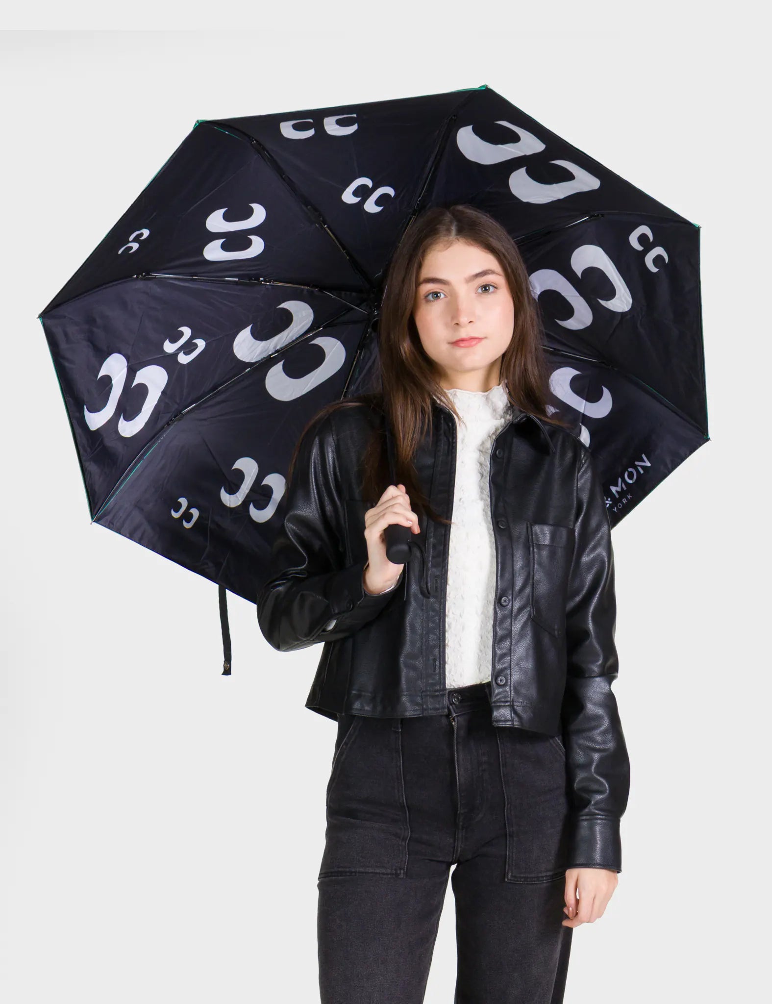 Person holding a black umbrella with white patterns against a white background