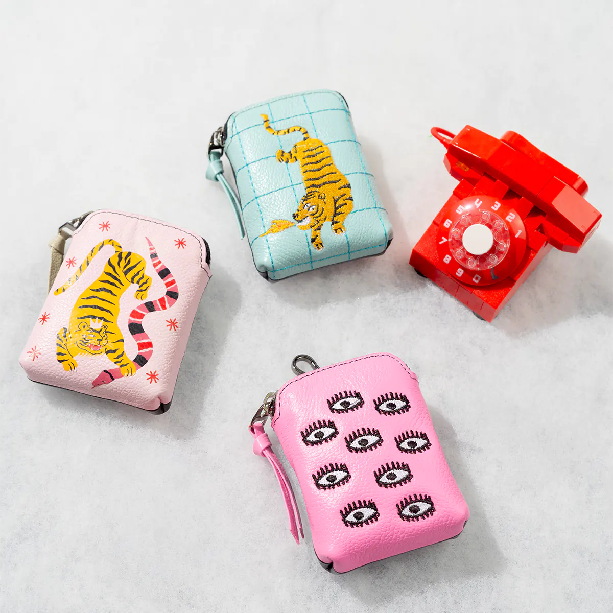 Close-up of colorful leather coin pouches with signature Min & Mon embroidery, styled on a minimal background.