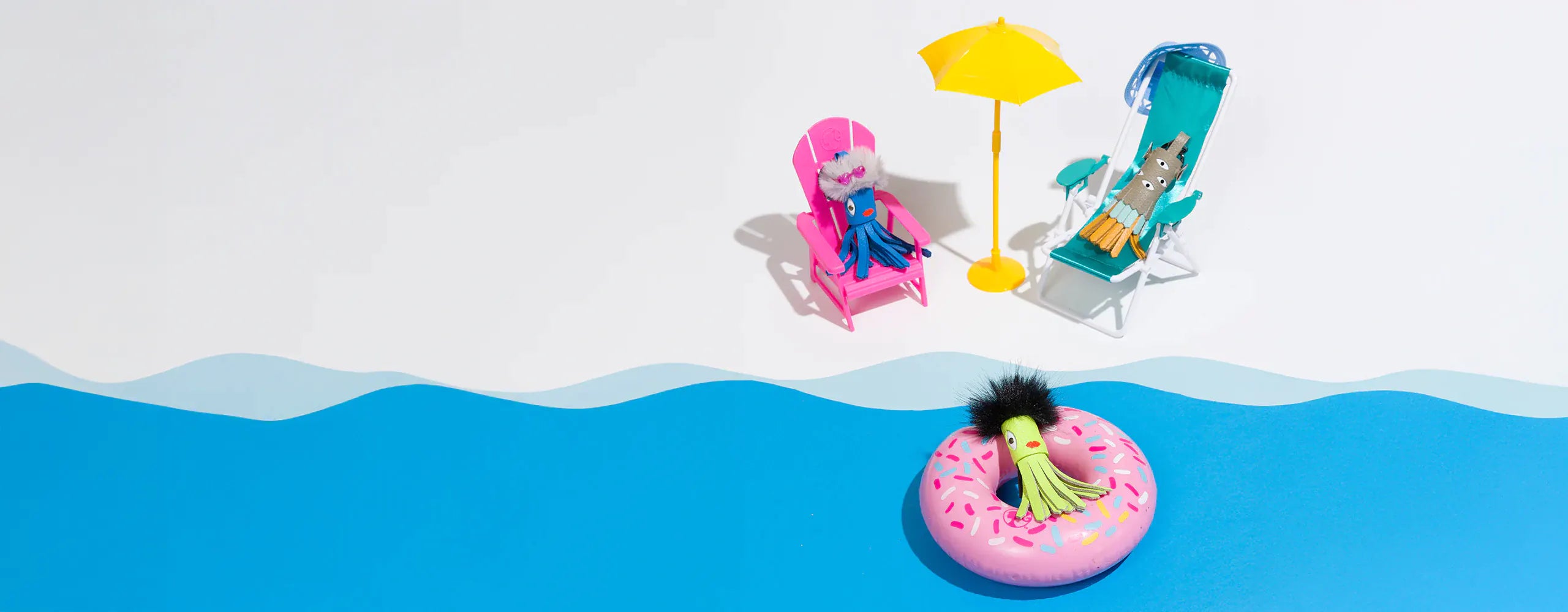 Mini colorful leather charms relaxing by a playful poolside scene with beach chairs, umbrella, and float.