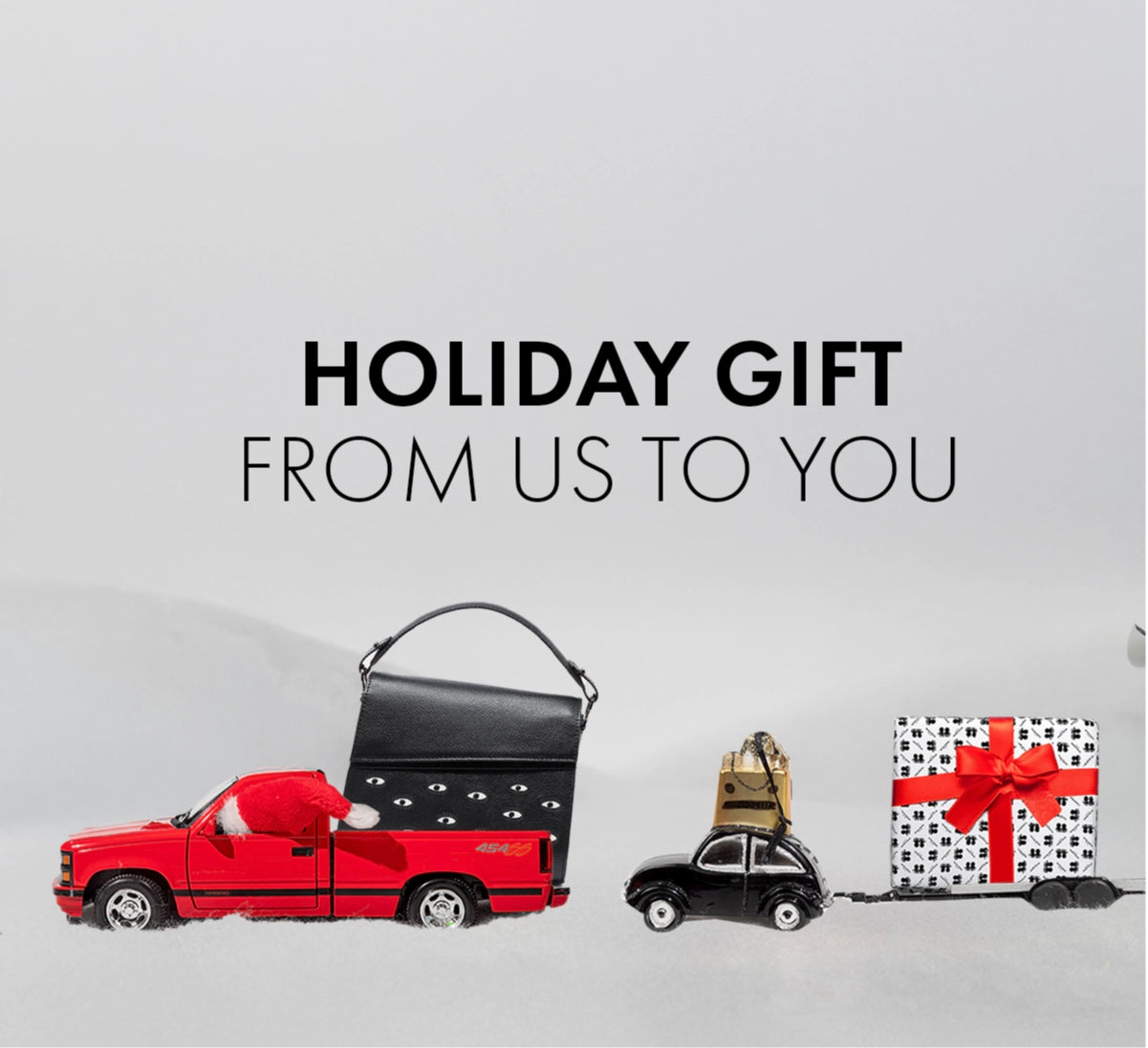 Holiday Gift From Us to You image showing a Min & Mon bag on a red toy truck with festive gifts in a winter setting.