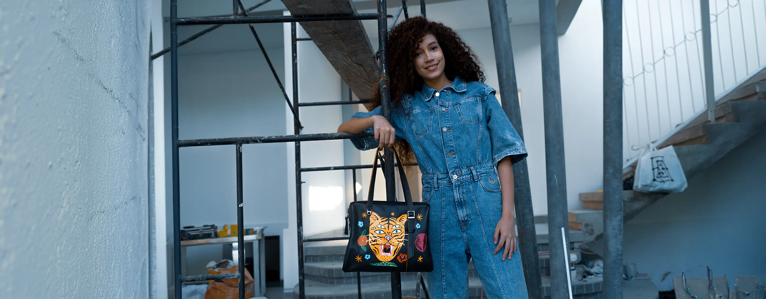 Black leather tote bag with bold embroidered tiger face, styled in an urban setting.