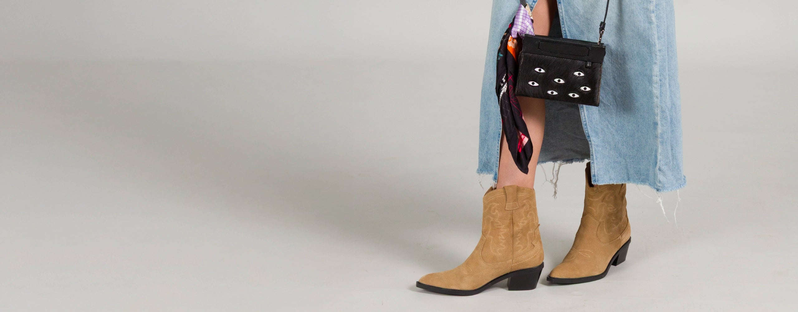 Model wearing Min & Mon black leather crossbody bag with embroidered white eyes, part of the Best Sellers collection.