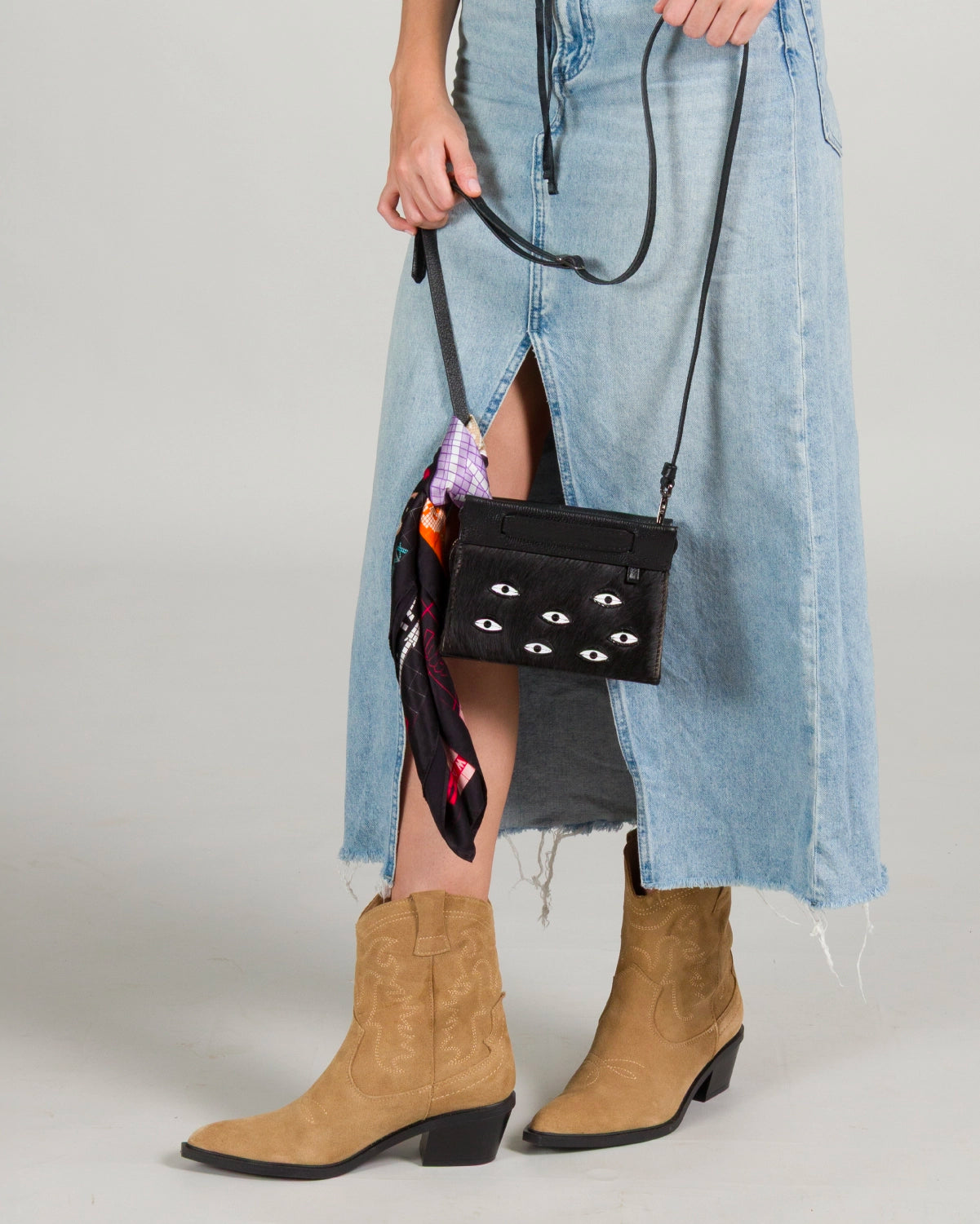 Close-up of Min & Mon best-selling black leather bag with signature eye embroidery and colorful scarf detail.