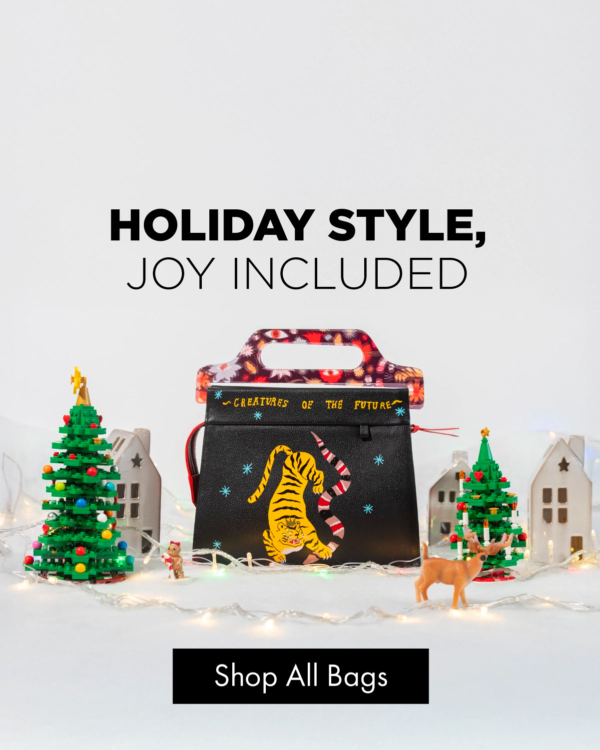 Min & Mon holiday handbag display with a black embroidered tiger bag, Christmas trees, and warm festive lights.
