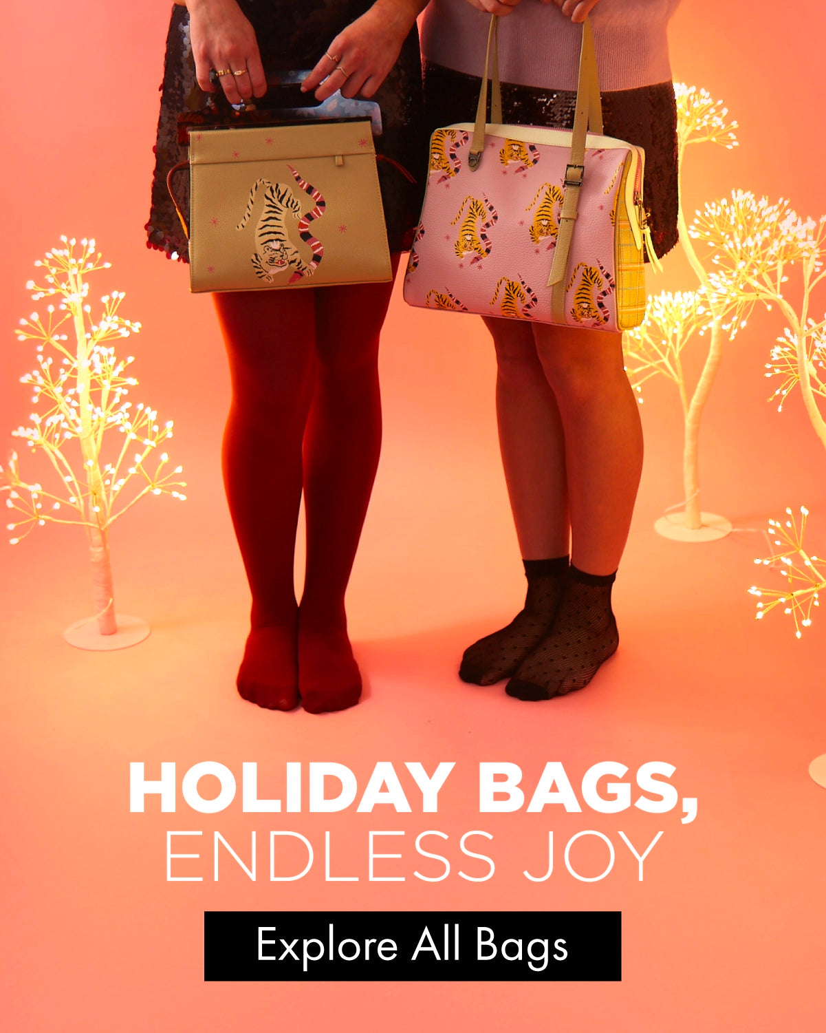 Two women standing in a pink holiday set holding Min & Mon tiger-print bags, surrounded by glowing decorative trees.