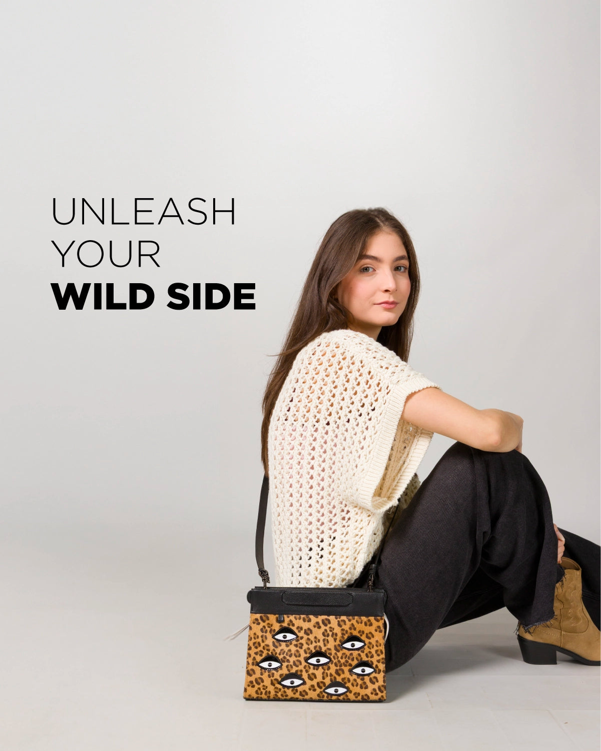 Model sitting on the floor wearing neutral tones and boots, holding a Min & Mon leopard-print handbag with embroidered eyes. Text reads “Unleash Your Wild Side.”