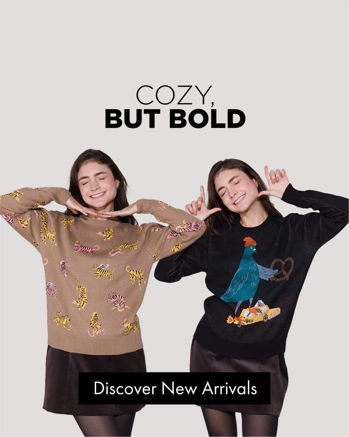 Two smiling models wearing bold, illustrated knit sweaters by Min & Mon, playful attitude on a neutral background.