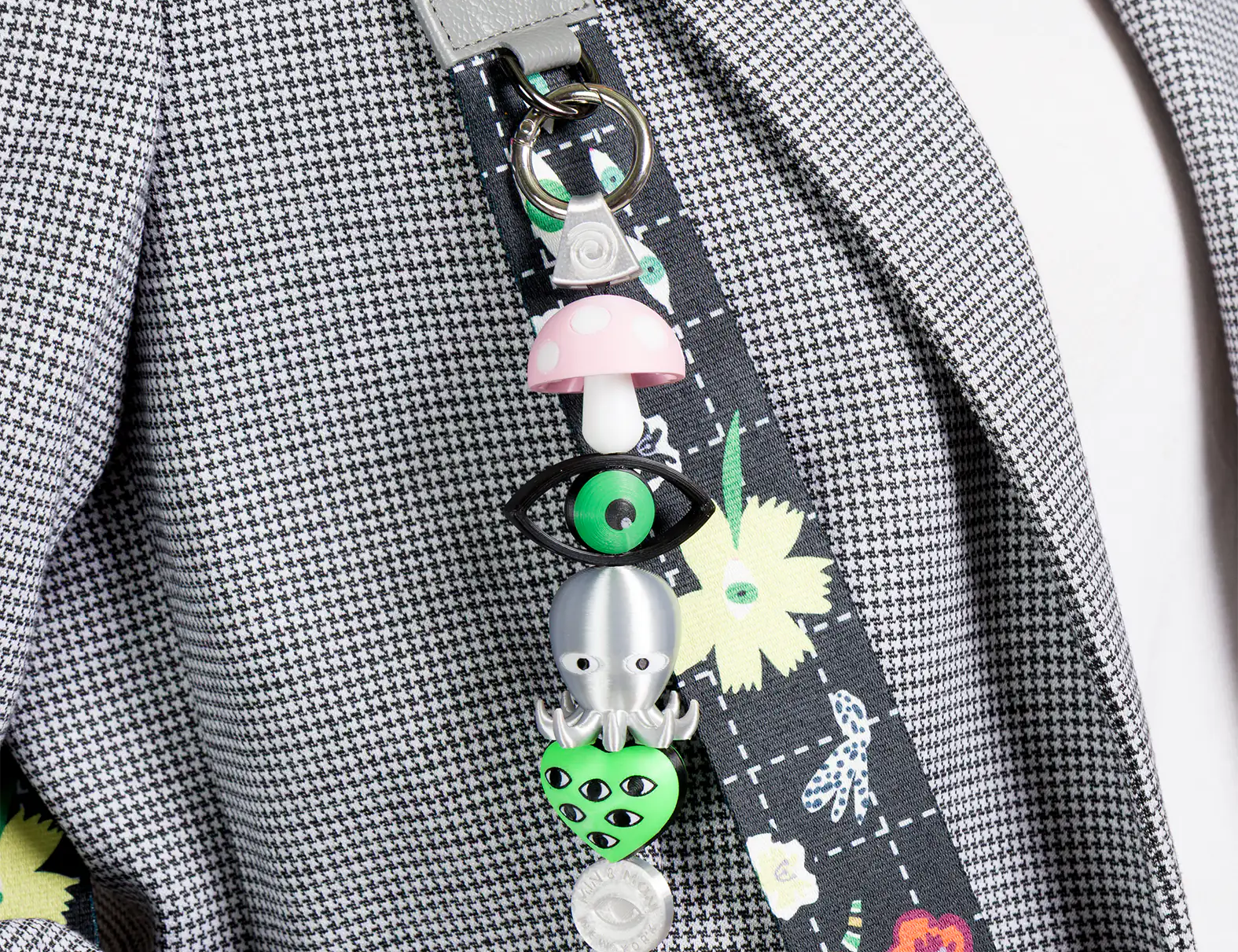 Decorative lanyard with colorful charms on a gray checkered jacket.