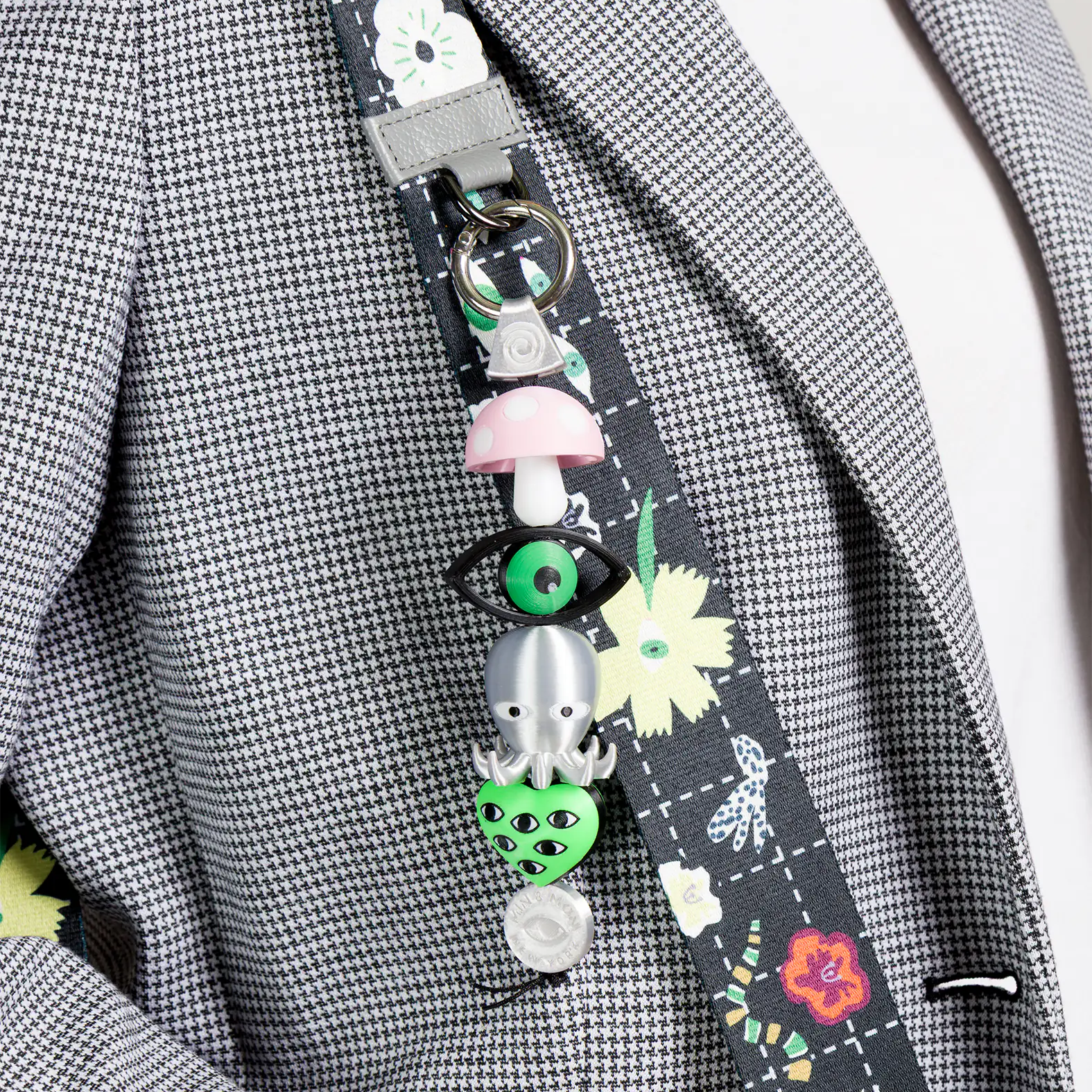 Decorative lanyard with colorful charms on a gray checkered jacket.