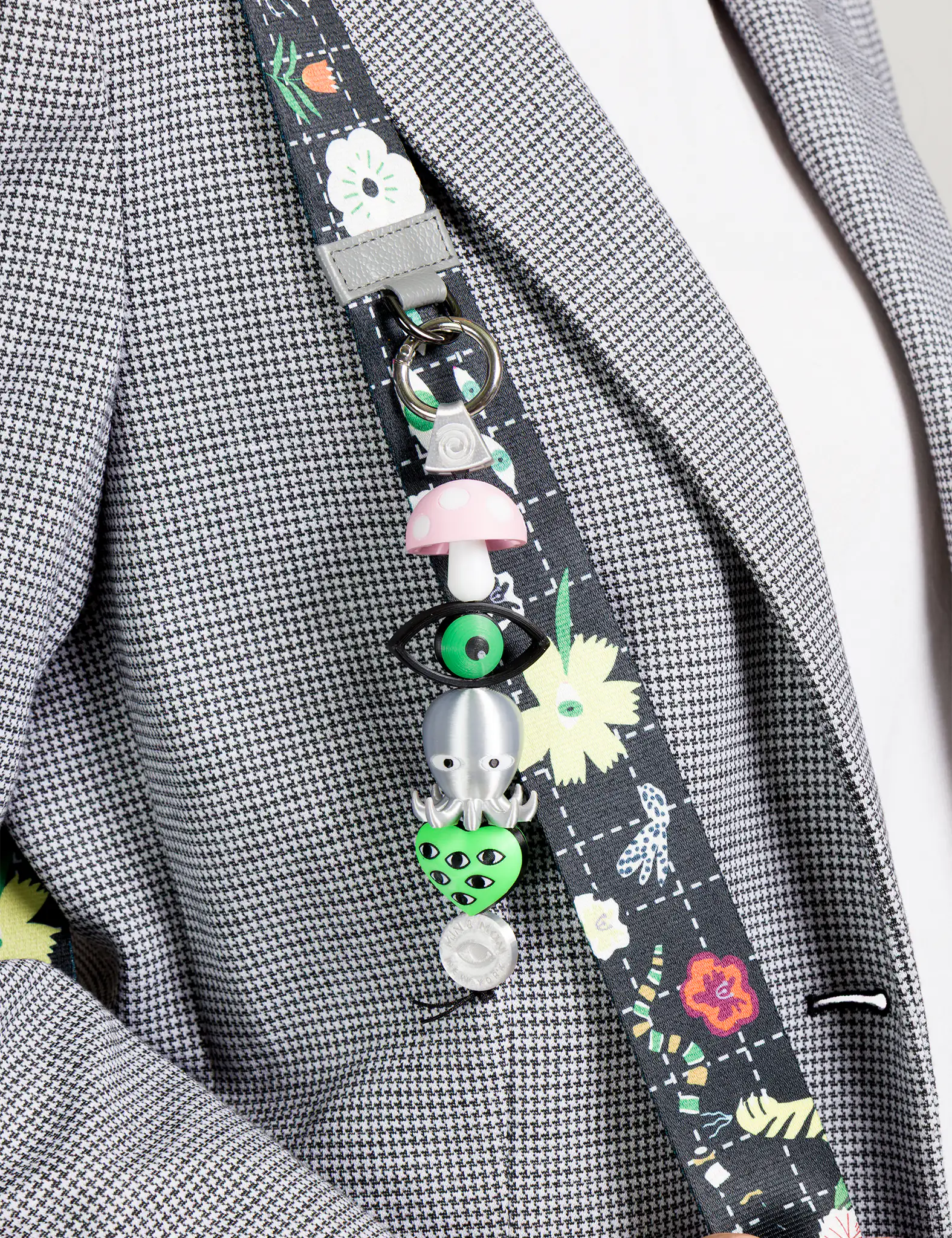 Decorative lanyard with colorful charms on a gray checkered jacket.