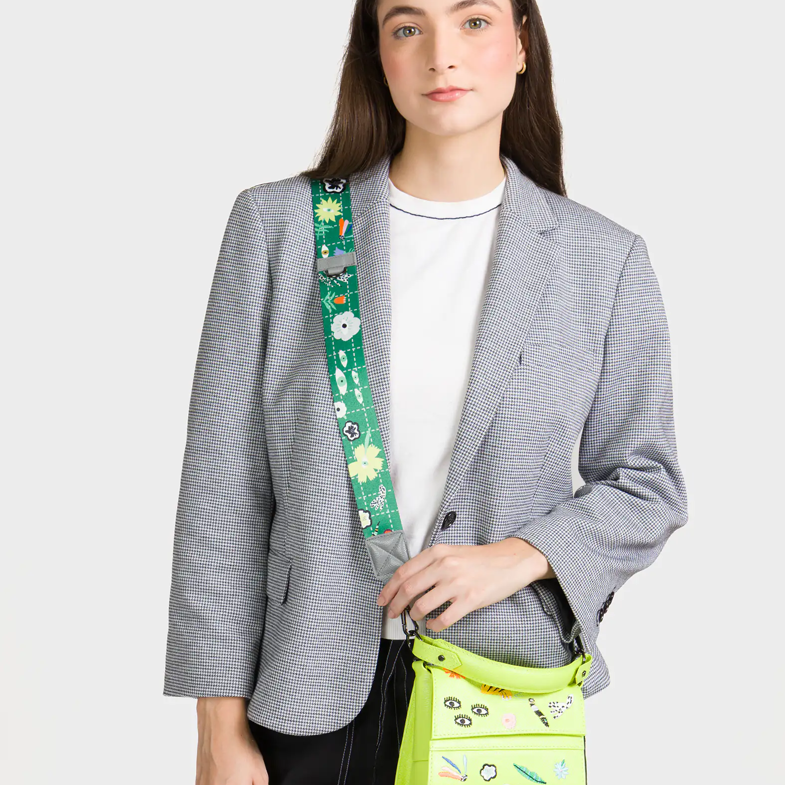Woman wearing a gray blazer with a green crossbody bag featuring colorful designs.