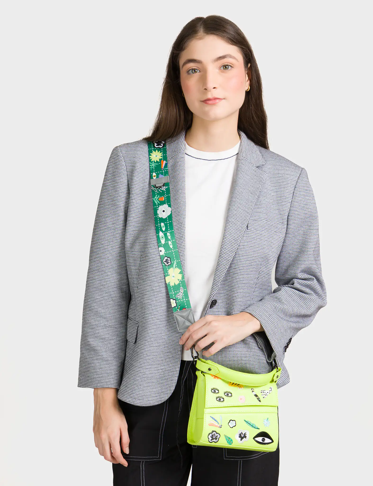 Woman wearing a gray blazer with a green crossbody bag featuring colorful designs.