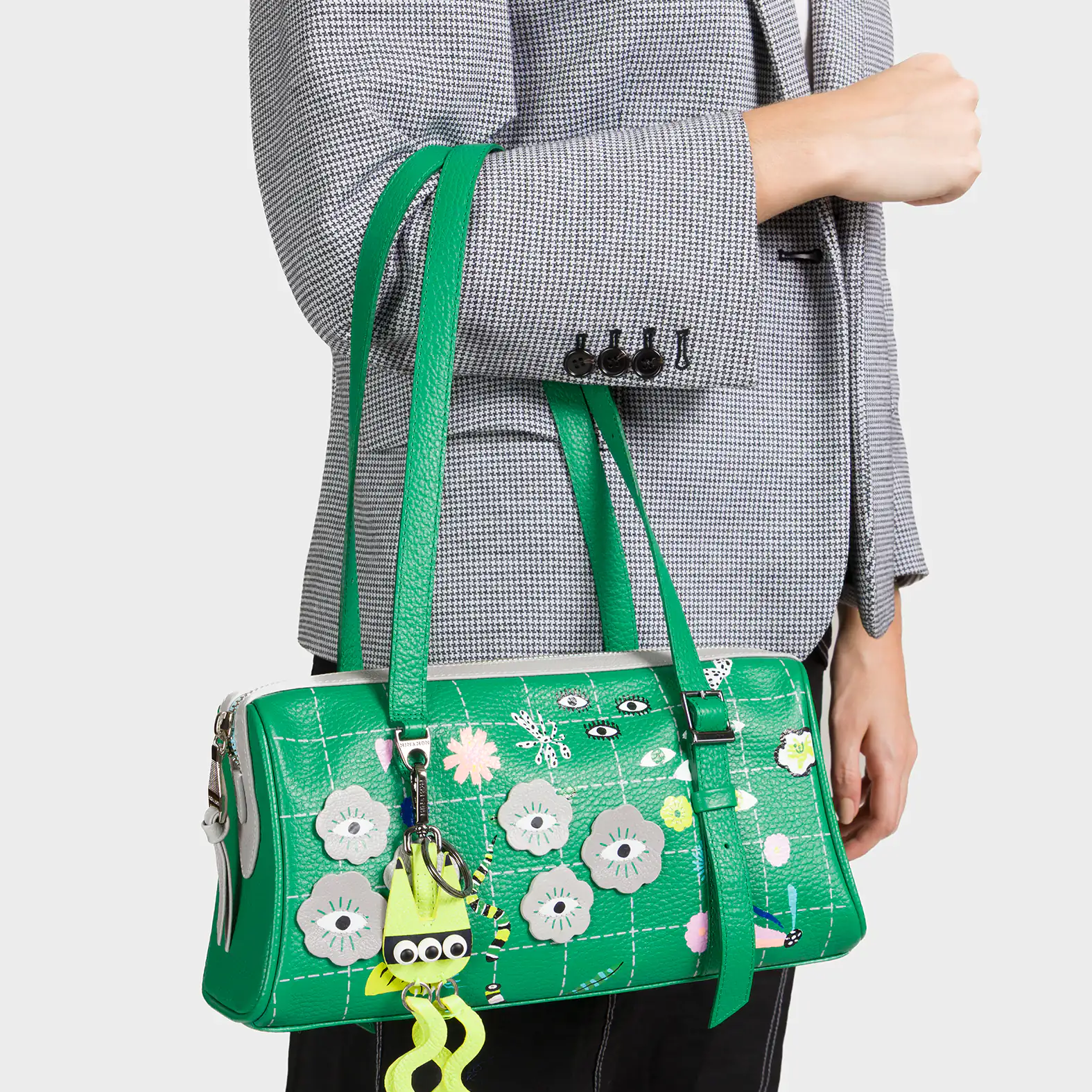 Green floral handbag with a unique design held by a person wearing a gray blazer.