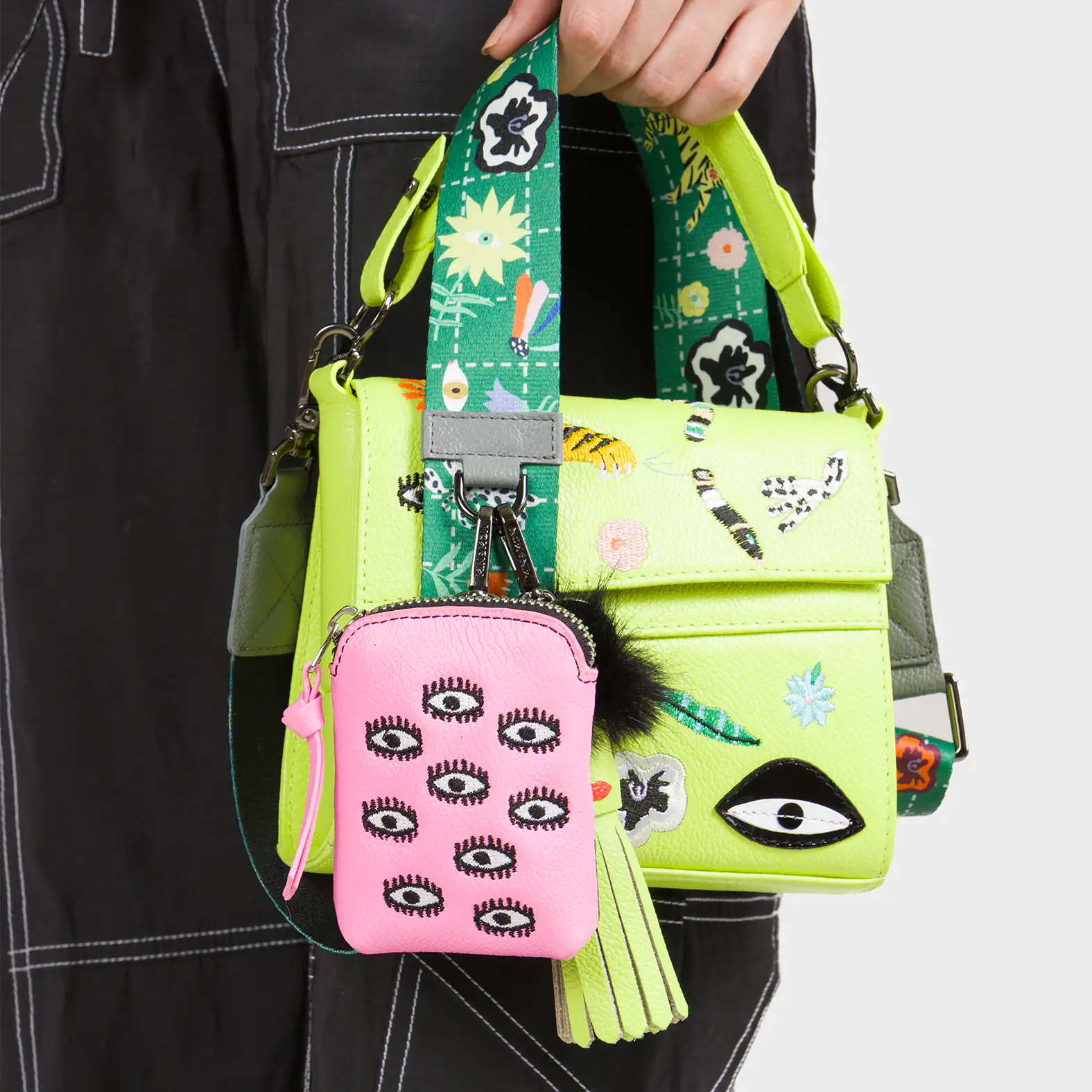 Person holding a colorful handbag with a matching small pouch featuring eye designs.
