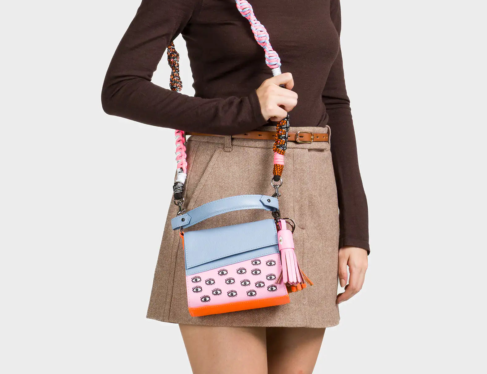 Person wearing a brown turtleneck and beige skirt holding a colorful handbag.