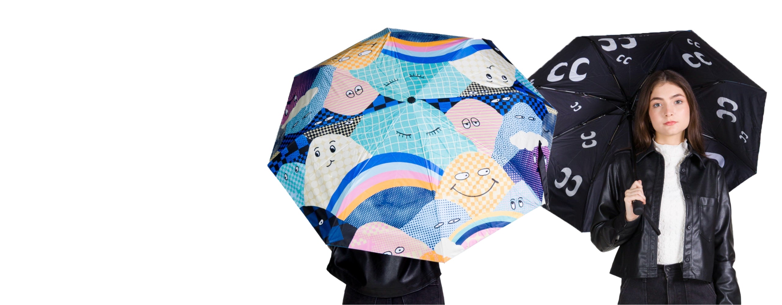 Model holding two Min & Mon umbrellas, one with colorful mountains and rainbow print and one black umbrella with eye logo pattern.
