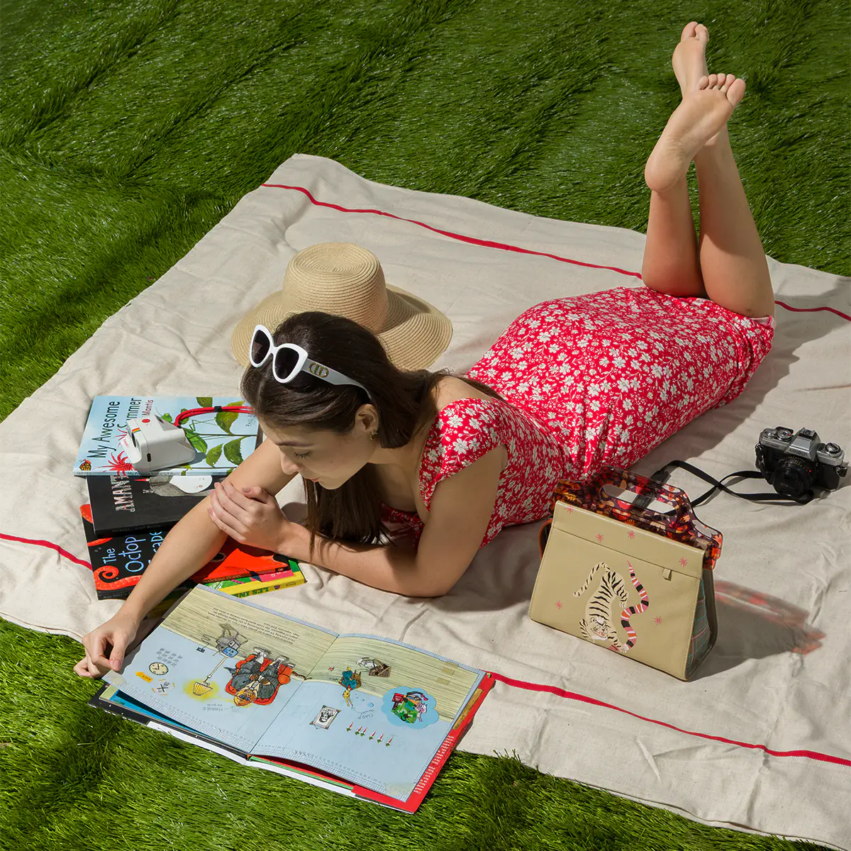 Lifestyle photo of a woman relaxing on a picnic blanket with a Retro Tiger Min & Mon handbag on the grass.