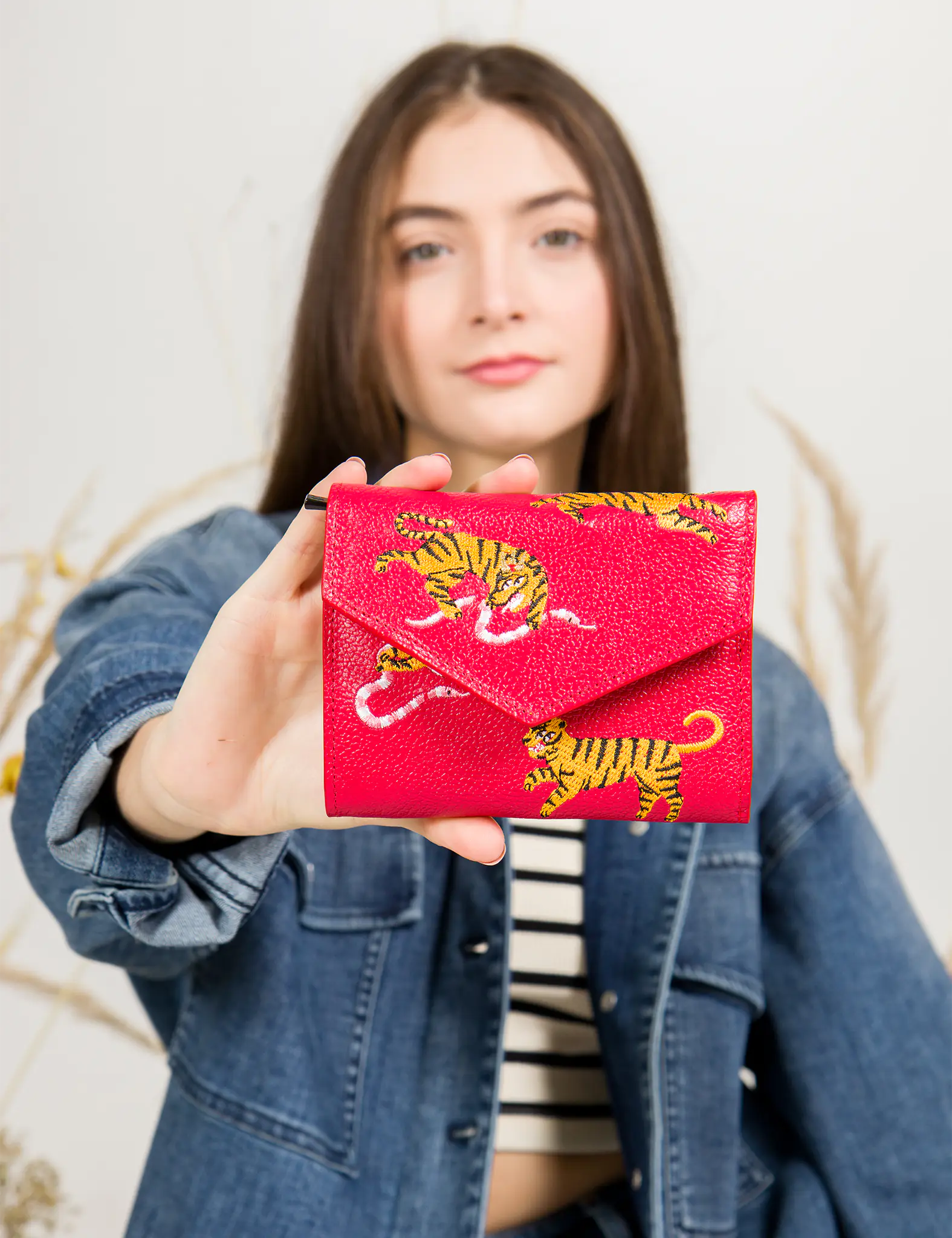 Person holding a red cardholder with tiger design against a neutral background