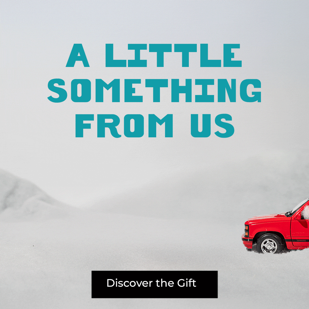 Animated banner reading “A Little Something From Us,” showing a toy car carrying a Min & Mon bag, followed by a smaller car pulling a wrapped gift, inviting users to discover the holiday gift promotion.