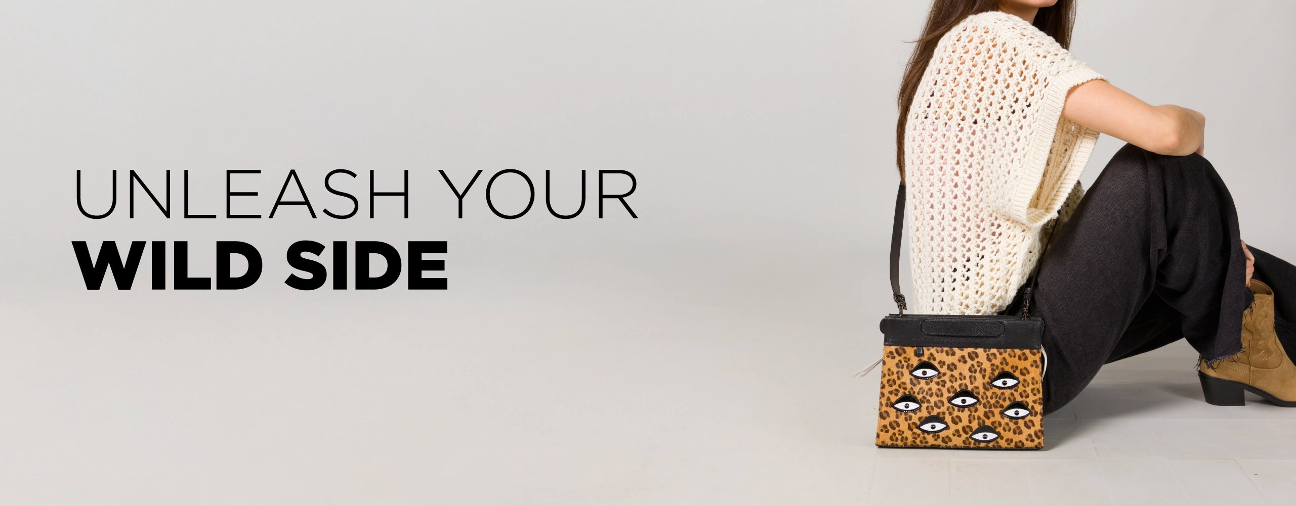 Model sitting on the floor wearing neutral tones and boots, holding a Min & Mon leopard-print handbag with embroidered eyes. Text reads “Unleash Your Wild Side.”