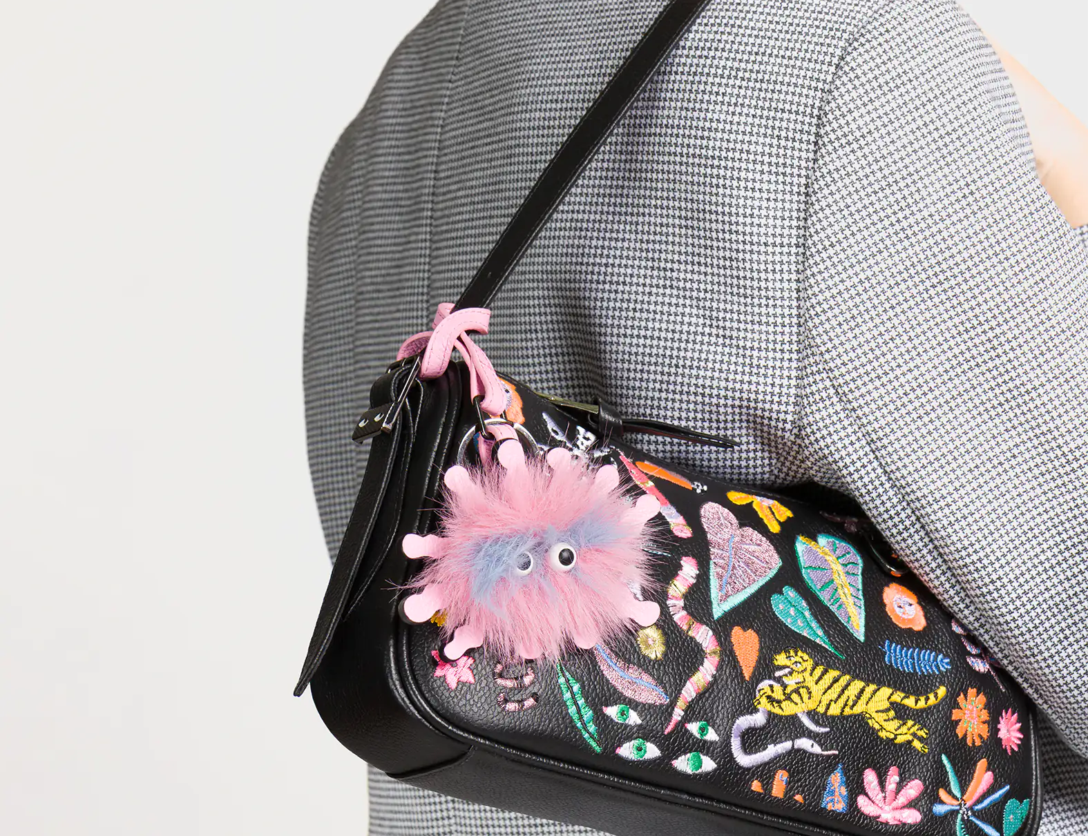 Person wearing a colorful handbag with abstract designs on a plain background