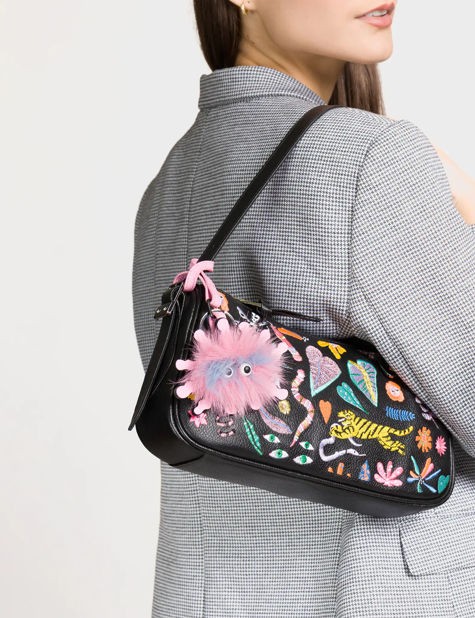 Person wearing a colorful handbag with abstract designs on a plain background